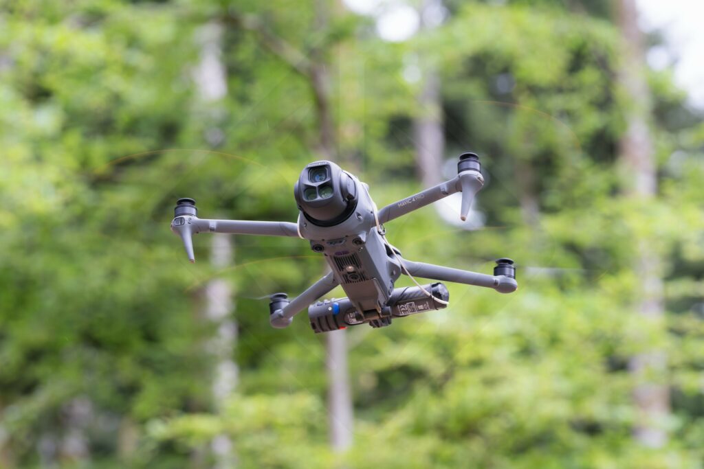 Drone professionnel en plein vol au-dessus d'une forêt, utilisé pour une captation vidéo d'entreprise